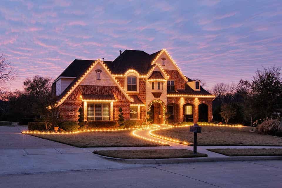 Residential home decorated with elegant holiday lighting at dusk
