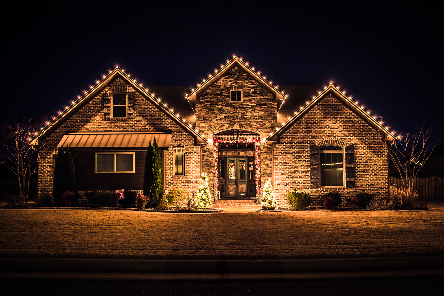 Residential holiday lighting installation by TruScape - TruScape Brick home decorated with professional holiday lighting at night